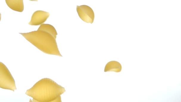 Detailní záběr suché těstoviny Conchiglie rigate létání diagonálně na bílém pozadí — Stock video