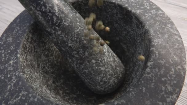 Primer plano de granos de pimienta verde cayendo en el mortero de piedra gris — Vídeos de Stock