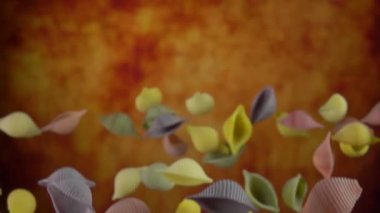 Kuru renkli makarna Conchiglie rigate sarı bir arkaplanda uçuyor.