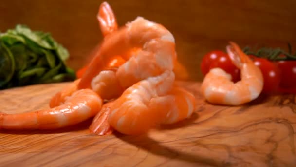 Close-up of delicious peeled shrimps falling on the wooden board — Stock Video
