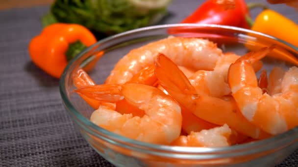 Close-up of a hand put a udang in a glass bowl on the background of tomato — Stok Video