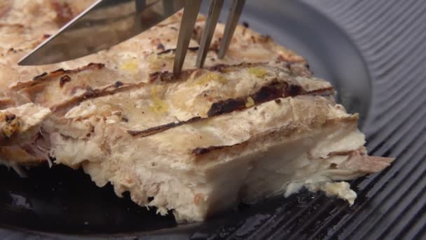 Супер крупный план ножа и вилки, берущей кусок жареной белой рыбы — стоковое видео