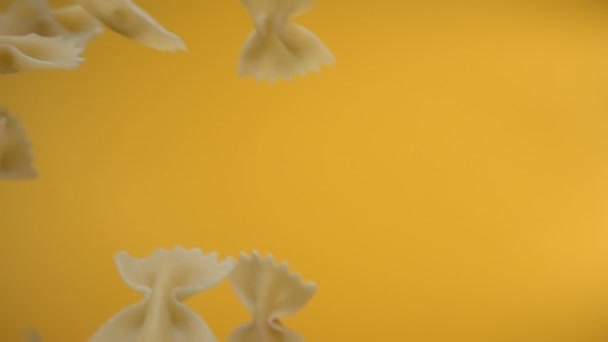 Farfalle 'ın sarı arka planda çapraz uçan kuru makarna yakın plan. — Stok video
