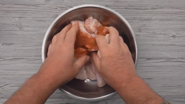 男性の手は、スパイスで鶏の羽を振りかけ、それらを混合している — ストック動画