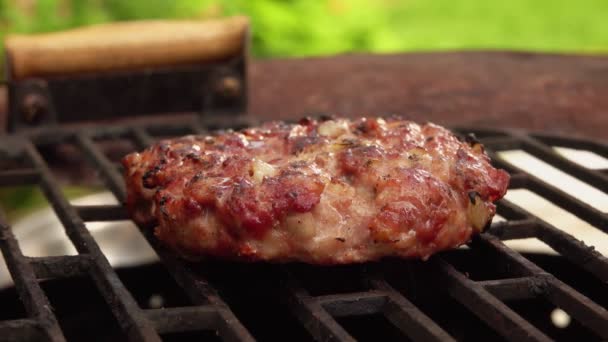 Uma deliciosa costeleta de carne caseira para um hambúrguer é virada na grelha — Vídeo de Stock