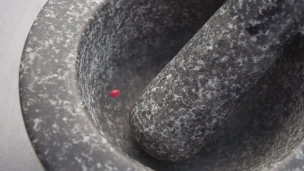 Close-up of rose-red peppercorns falling into the grey stone mortar — Stock Video
