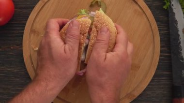 Erkek ellerinin iki parçaya bölünmüş taze ev yapımı ızgara burgeri açtığı en iyi manzara.