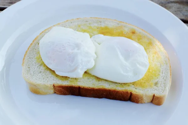 Tereyağlı tost üzerinde iki haşlanmış yumurta 