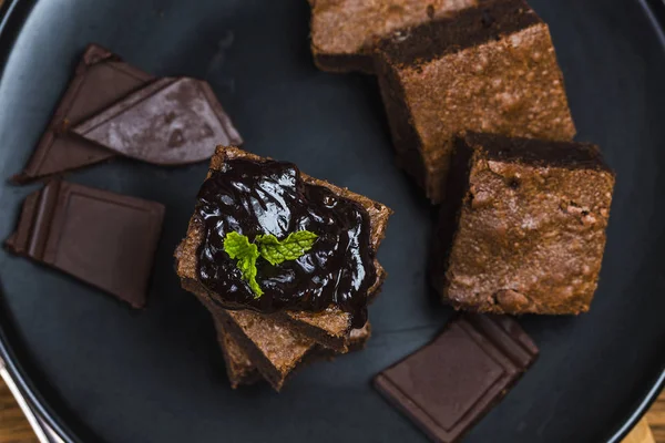 Homemade dark chocolate brownies topping with almond slices and mint stacked on wood table with copy space. Delicious bitter sweet and fudge. Brownie is one type of chocolate cake.