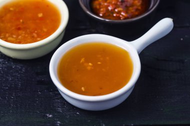 Siyah ahşap masadaki kâselerde çeşitli soslar. 