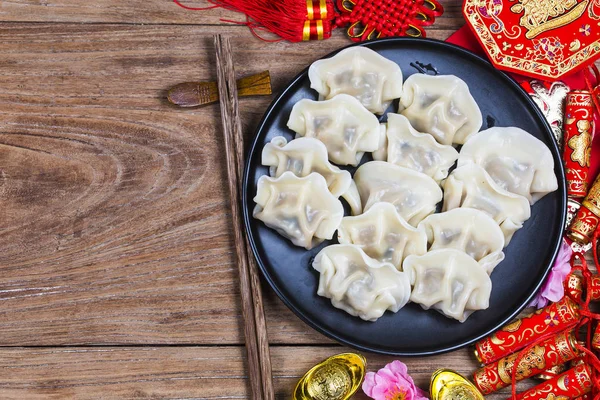 Chinese Jiaozi new year food, spring festival food on traditional spring festival Spring festival atmosphere and dumplings, ang pow or red packet and gold ingots. Chinese characters means luck,wealth