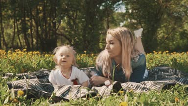 Anne ve kızı açık çim üzerinde yalan. Mutluluk annelik ve çocukluk