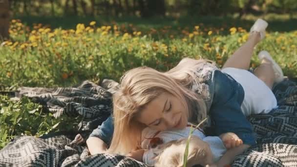 Madre e hija tumbadas en el césped. Familia en parque de la ciudad al aire libre — Vídeos de Stock