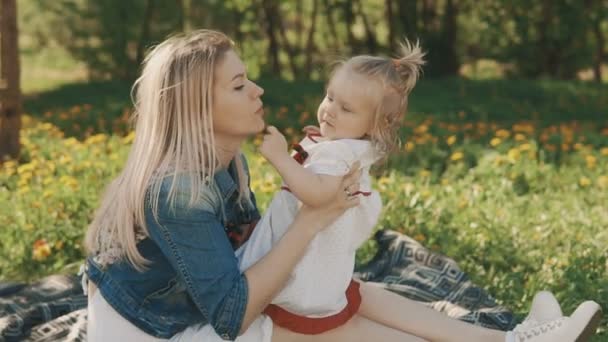 Madre e hija tumbadas en el césped. Felicidad de la maternidad y la infancia — Vídeos de Stock