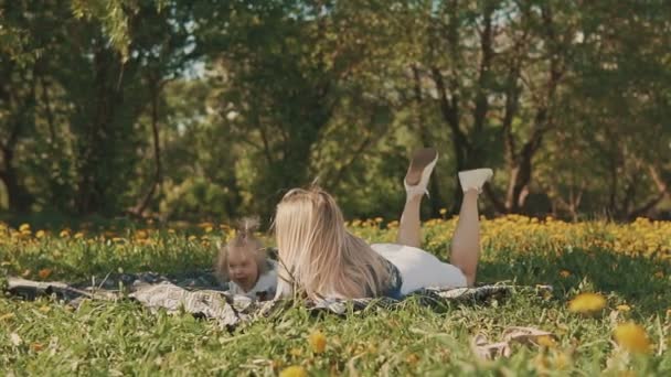 Moeder en dochter liggen op gazon. Familie in stadspark buitenshuis — Stockvideo
