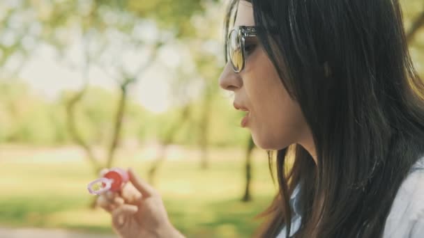 Chica hipster alegre con gafas de sol que se divierten haciendo burbujas en cámara lenta — Vídeos de Stock