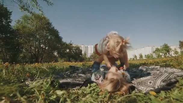 Moeder en dochter liggen op gazon. Familie plezier in stadspark buitenshuis — Stockvideo