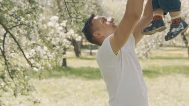 Babalık kavramı. Genç baba ve küçük oğlu açık havada ağır çekimde iyi eğlenceler