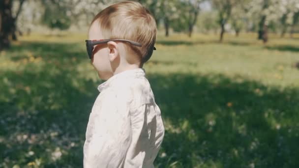Kid stay in sunglasse s in city park in slow motion — Stock Video