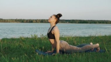 Güzel bir kadın sabah Yoga uygulamak. Yoga yaparken kız yeşil çimenlerin üzerinde hareket eder.