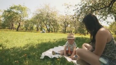 Mutlu genç anne sevimli oğlu Park'ta ağacın altında battaniyeyle oynuyor