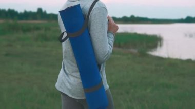 Genç kız sahilinde Yoga pratik yapmak için yürüyüş. Kadın holding mavi yoga mat