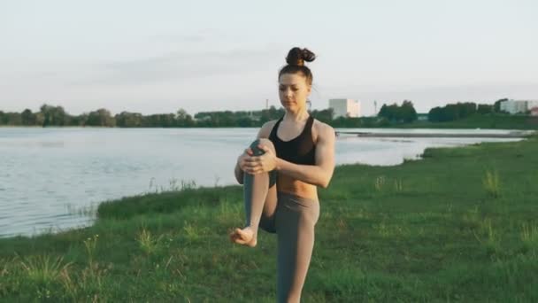 Mujer morena practicando yoga en el parque. Chica haciendo yoga se mueve sobre hierba verde — Vídeo de stock
