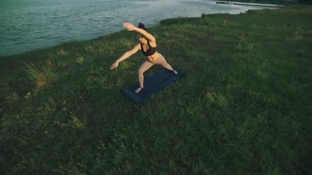 Mujer morena practicando yoga en el parque. Chica haciendo yoga se mueve sobre hierba verde — Vídeo de stock