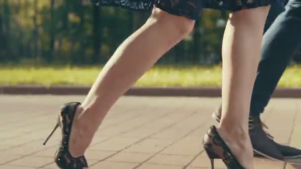 Closeup mladých páry nohou, protože procházka parkem při západu slunce — Stock video