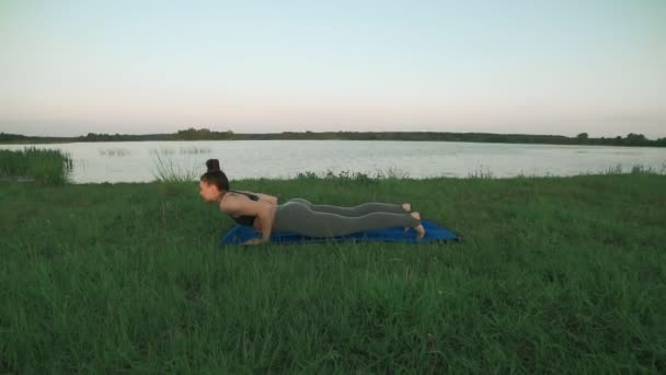 Hermosa joven haciendo yoga en la mañana en el lago. concepto de estilo de vida saludable — Vídeos de Stock