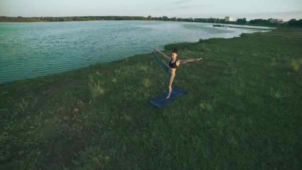 Menina bonita praticando ioga no parque da manhã. Morena mulher fazendo ioga — Vídeo de Stock