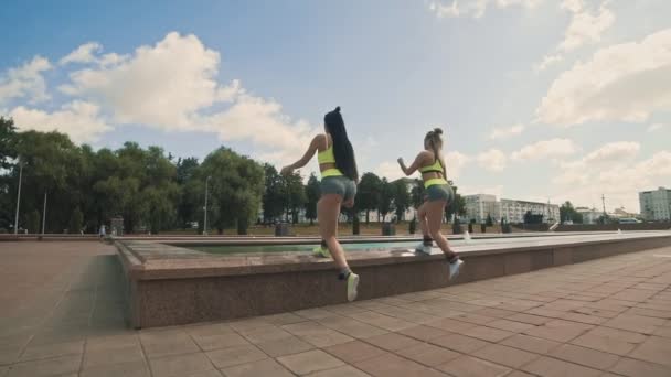 Las mujeres de fitness haciendo ejercicio al aire libre en el soleado día de verano en ropa deportiva verde — Vídeos de Stock