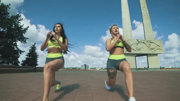 Dos modelos de fitness para mujeres haciendo ejercicio Lunge en la ciudad en día soleado — Vídeo de stock