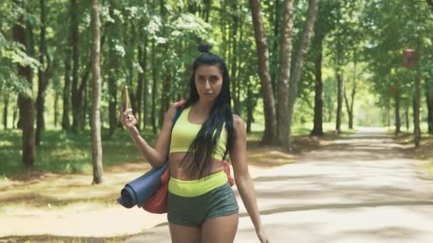 Chica morena atractiva charlando antes de correr. Concepto tecnológico — Vídeos de Stock