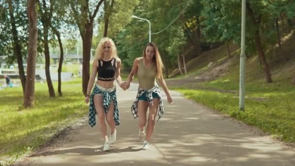 Schattig hipster girls in shorts springt in park. Jonge meisjes veel plezier en buitenshuis — Stockvideo