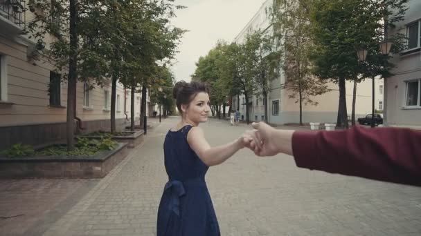 Young couple holding hands woman leading boyfriend running in street — Stock Video