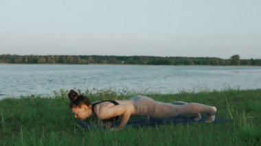 Esmer kadın pratik yoga Park. Yoga yaparken kız yeşil çimenlerin üzerinde hareket eder.