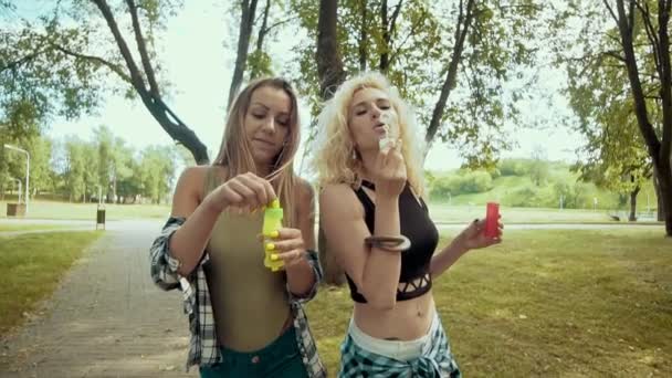 Happy hipster girls with sunglasses having fun making bubbles in park — Stock Video