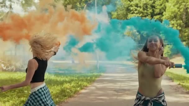 Молоді дівчата розважаються з кольоровим димом і стрибають на відкритому повітрі в повільному русі — стокове відео