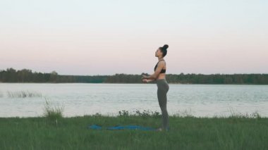 Güzel genç kadın mavi yoga mat sessiz sahne gündoğumu, yoga yaparken