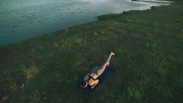 Mujer delgada practicando yoga por la mañana. Chica morena haciendo movimientos de yoga — Vídeo de stock