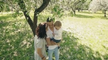 Gülümseyen Anne oğlu yaz elma ağacı Park gidiyor. Mutlu aile kavramı