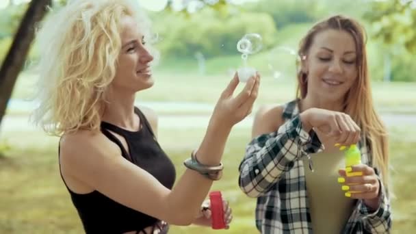 Joyeux hipster filles avec des lunettes de soleil avoir du plaisir à faire des bulles dans le parc en plein air — Video