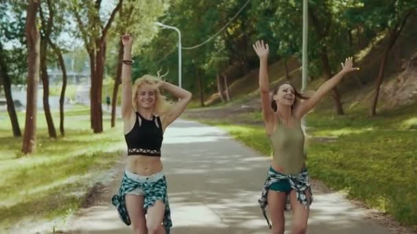 Jonge meisjes veel plezier en buitenshuis in slow motion. Dames in korte broek loopt in park — Stockvideo