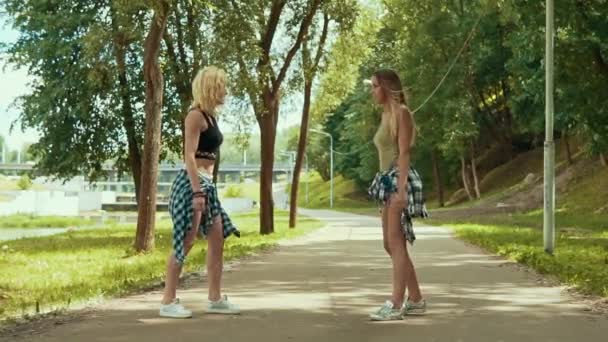 Mulheres impressionantes em shorts salta no parque. Meninas jovens se divertir e ao ar livre — Vídeo de Stock