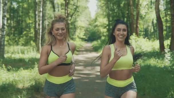 Mulheres bonitas a correr no parque. Meninas loiras e morenas correndo ao ar livre — Vídeo de Stock