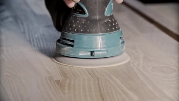 Stroje na broušení dřeva. Tesař pracující s elektrickou bruskou na povrchu stolu — Stock video