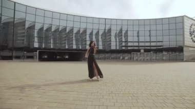 Zarif kadın siyah elbiseli cam building yakınındaki keman çalıyor. Sanat kavramı