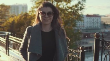 Güneş gözlüklü Şirin genç kız ceket sonbahar şehirde size yürür