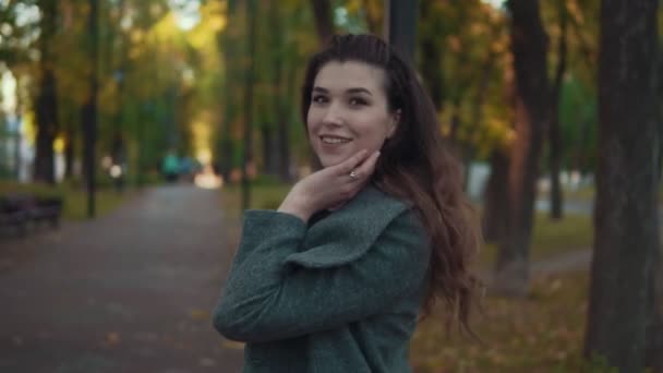 Incredibile ragazza con acconciatura riccia in cappotto camminare nel vicolo autunnale e sorridente — Video Stock